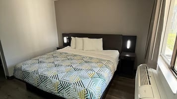 Une chambre d’hôtel moderne avec un grand lit, une table de chevet, un radiateur et une fenêtre avec des rideaux.