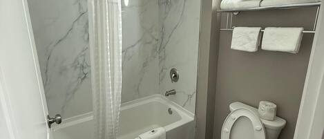 Un baño moderno con bañera, ducha e inodoro.