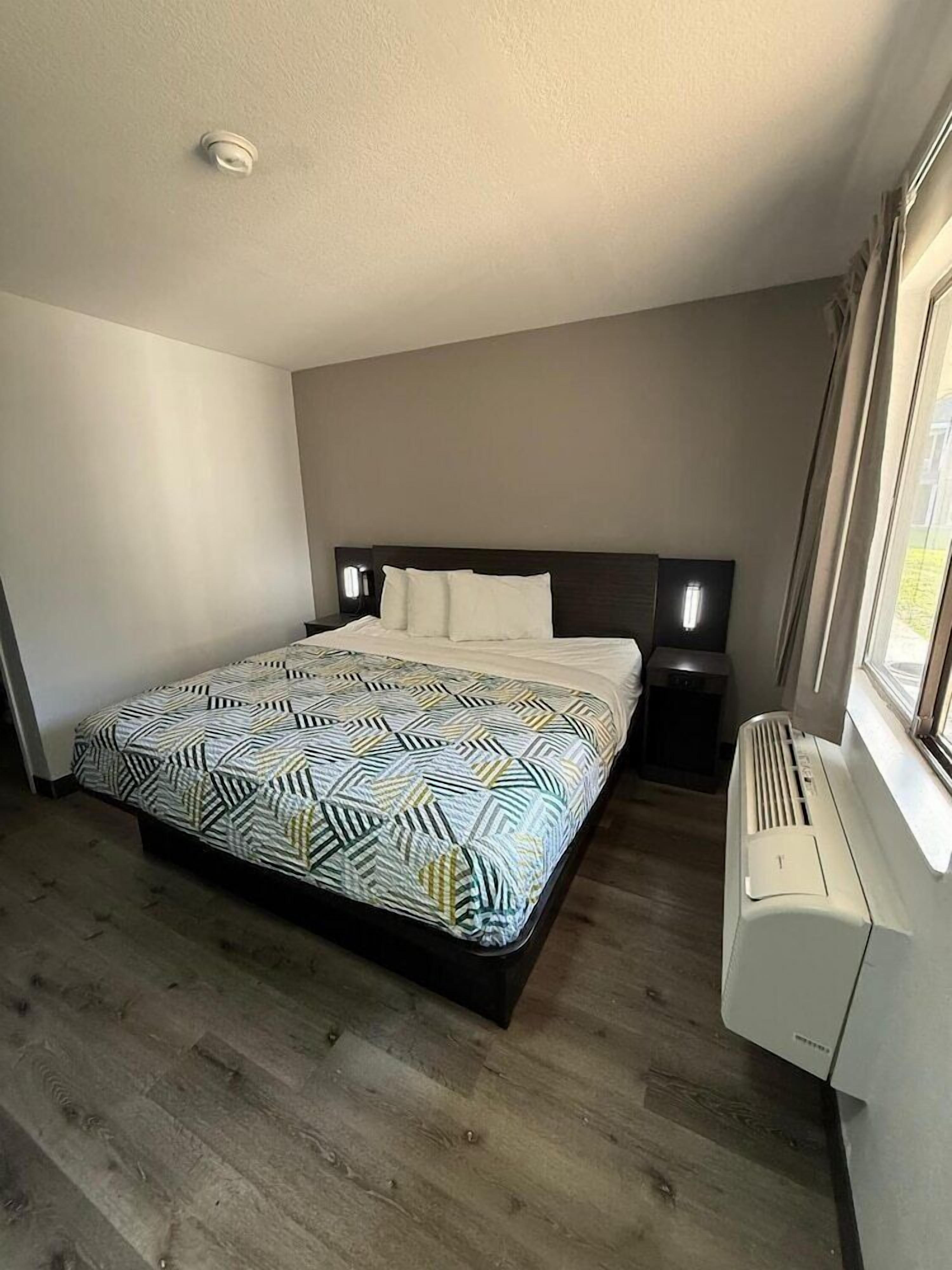 A bedroom with a bed, bedside tables, a heater, and a window.
