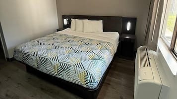 A bedroom with a bed, bedside tables, a heater, and a window.