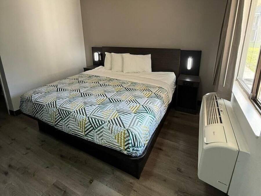 A bedroom with a bed, bedside tables, a heater, and a window.