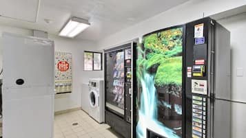 Un cuarto de lavandería con lavadora, secadora y máquina expendedora con fondo de cascada.