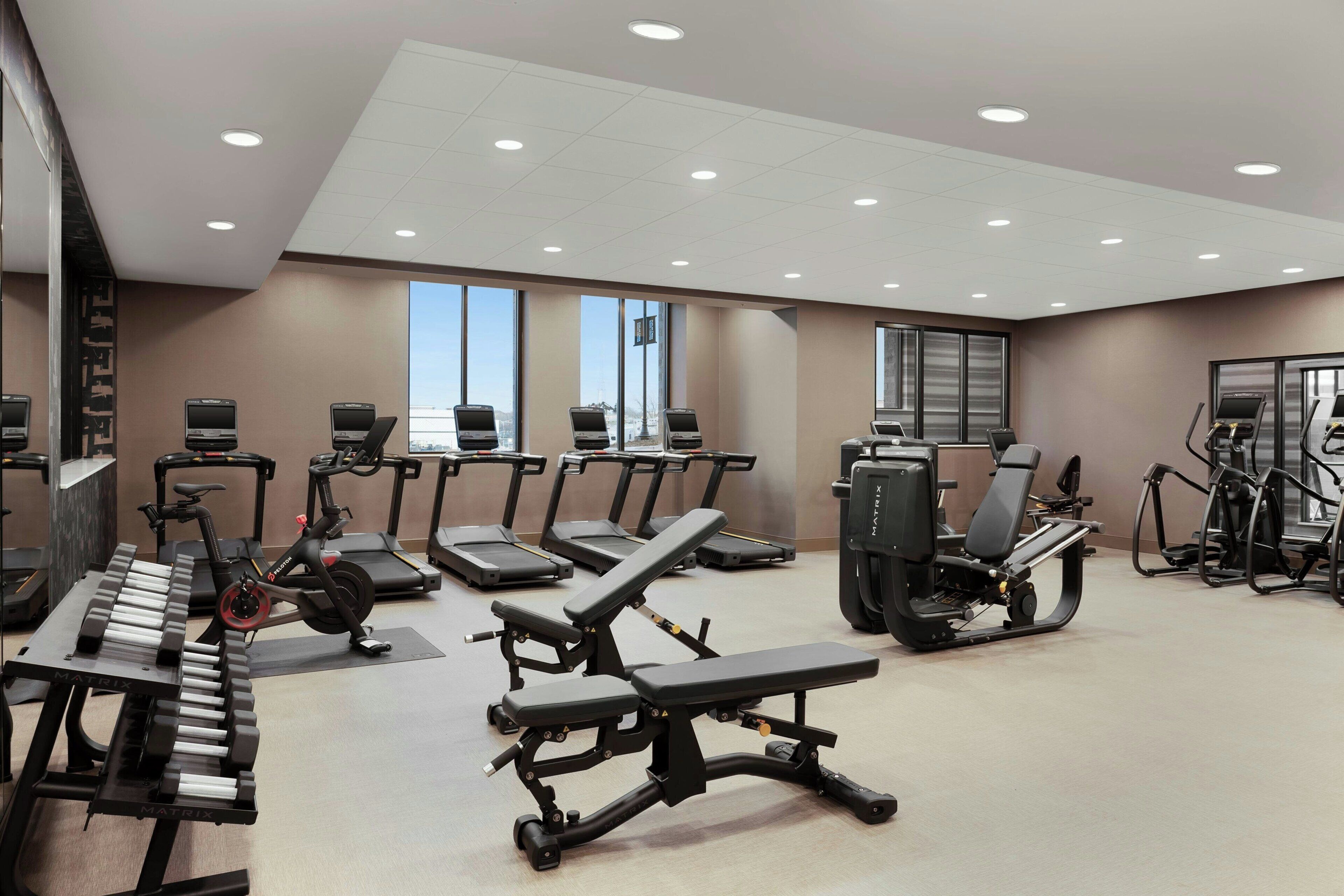 Une salle de sport moderne équipée de tapis de course, de vélos elliptiques et de bancs de musculation.