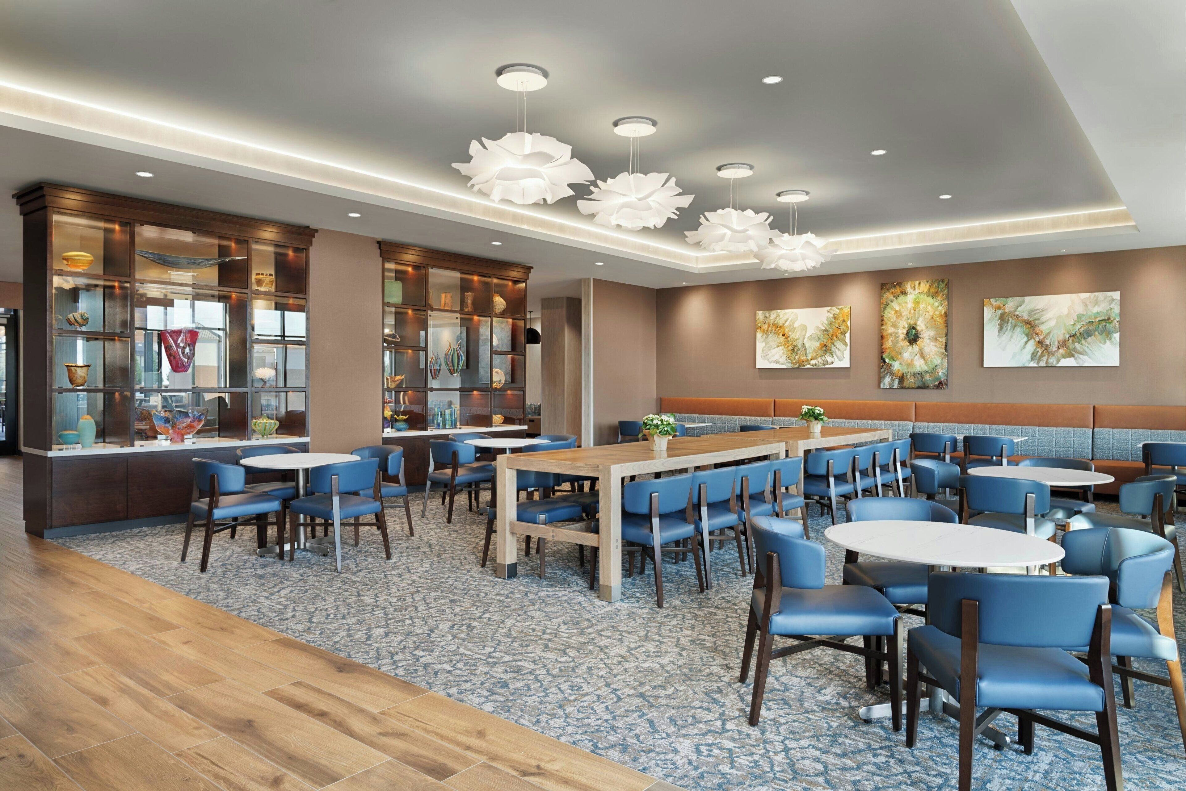 Un restaurant moderne avec des chaises bleues, des tables en bois et un îlot central.