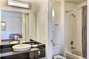 A bathroom with a sink, mirror, and shower.