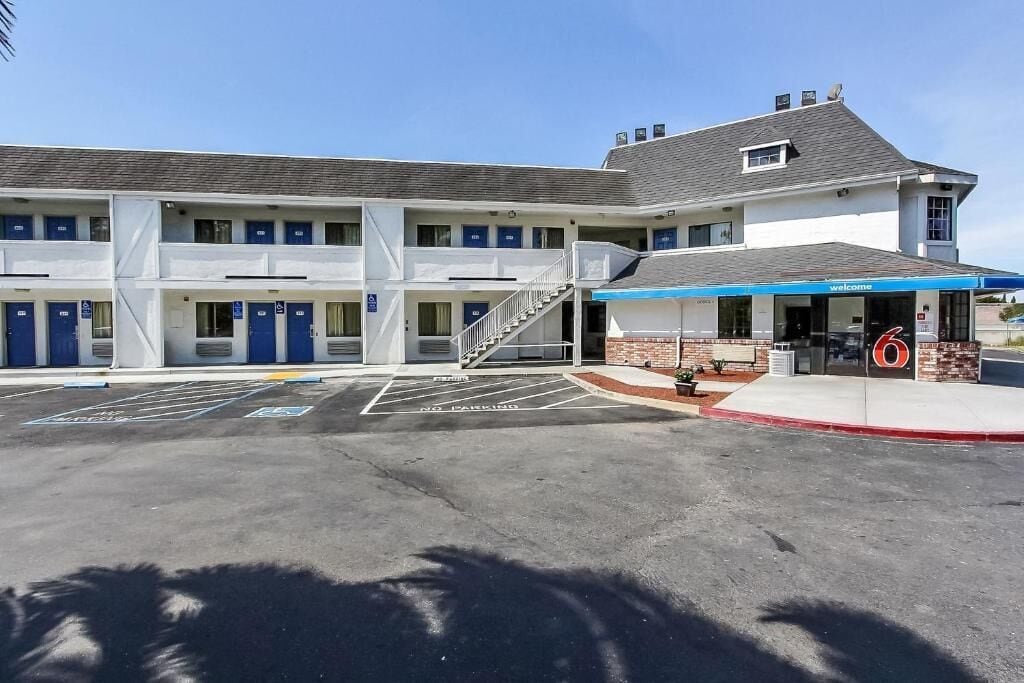 A motel with a central entrance, multiple rooms on each floor, and a parking lot with marked handicapped spaces.