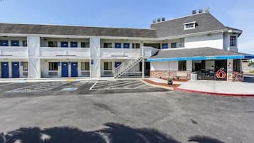 A motel with a central entrance, multiple rooms on each floor, and a parking lot with marked handicapped spaces.