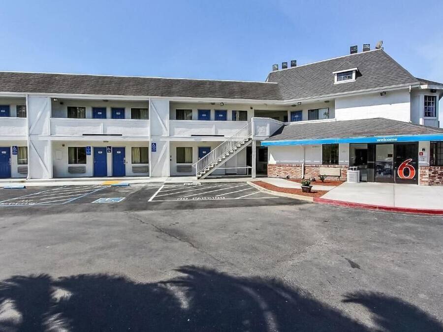 A motel with a central entrance, multiple rooms on each floor, and a parking lot with marked handicapped spaces.