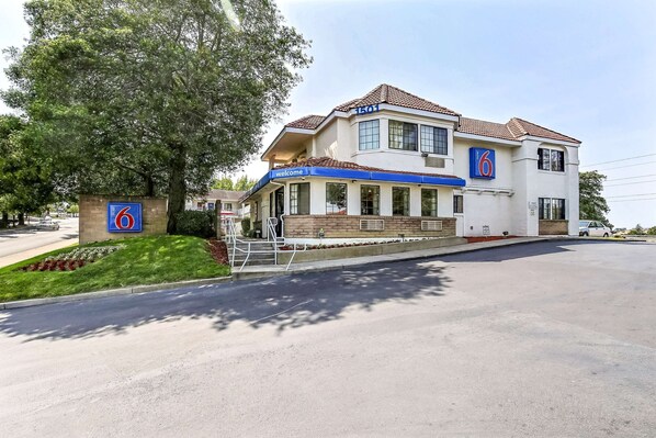 A two-story hotel with a '6' sign, a 'welcome' sign, and a large tree in front. - Motel 6 Pinole, CA (Pinole)