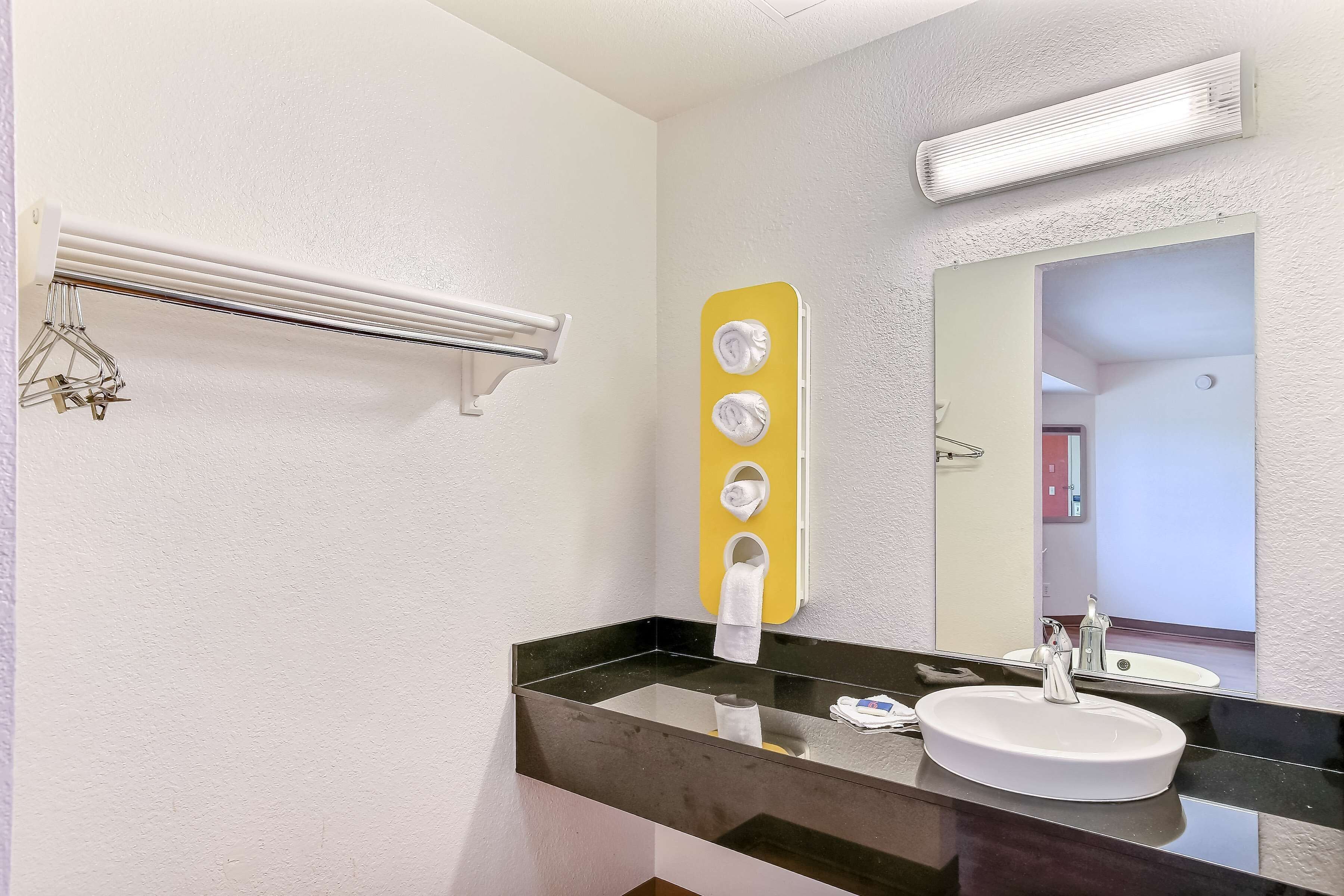 Un baño con lavamanos de encimera negra, un espejo, toallero y calentador de toallas.