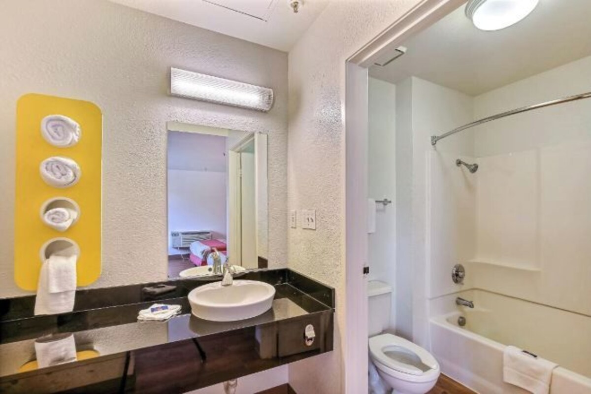 A bathroom with a sink, mirror, towel rack, and shower.