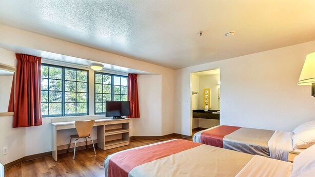 A hotel room with two beds, a desk with a chair, a television, and a window with curtains. - Motel 6 Pinole, CA (Pinole)