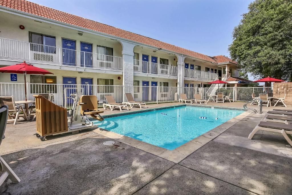Un hôtel doté d’une piscine, d’un espace extérieur aménagé et d’un bâtiment à deux étages avec des balcons.