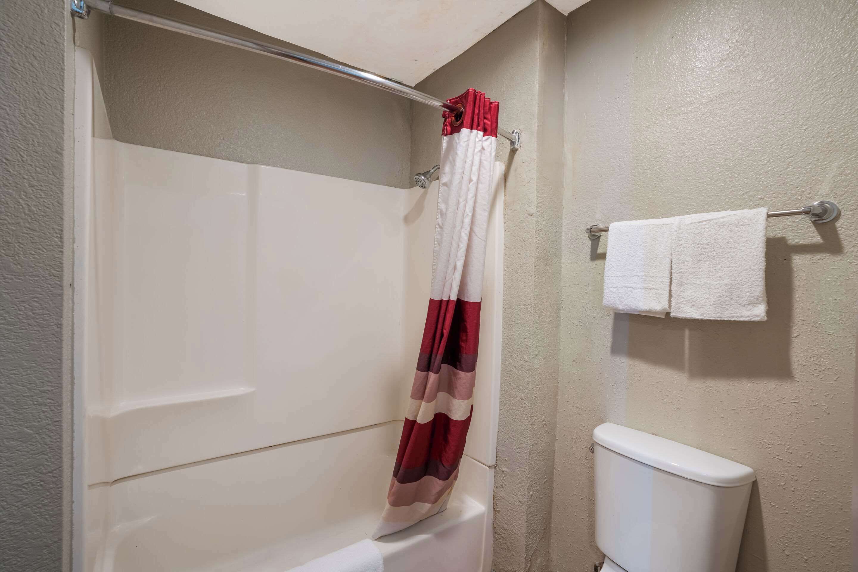 Un baño con cortina de ducha, inodoro y barra para toallas.