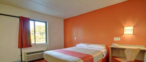 A bedroom with a bed, a desk, and a chair.