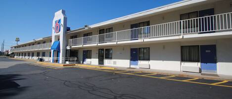 A motel with a 6-star sign, multiple rooms, and a parking lot.