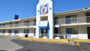 Un motel avec un grand panneau indiquant le chiffre « 6 », de nombreuses chambres et une entrée accueillante.