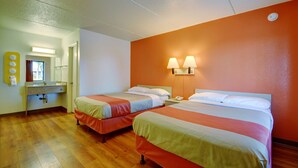 Une chambre d’hôtel avec deux lits, une salle de bain et un petit bureau.