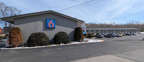 A motel with a '6' sign, a parking lot, and a building with a balcony.