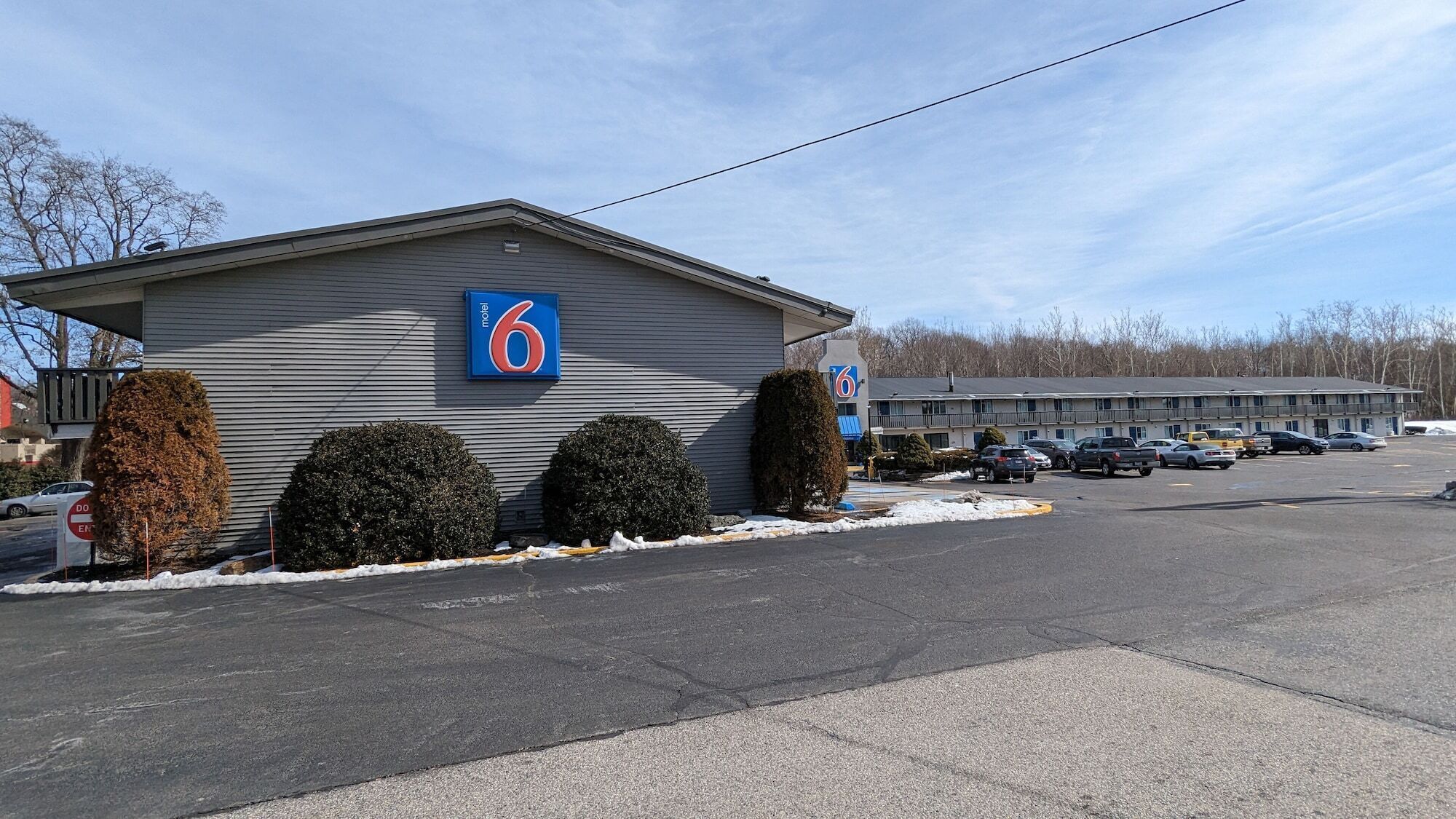 A motel with a '6' sign, a parking lot, and a building with a 'DO NOT ENTER' sign.