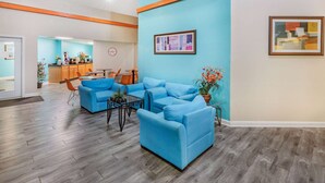 A spacious lobby with blue sofas, a coffee table, and a kitchen area in the background. - Howard Johnson by Wyndham Houston Hobby Airport (Houston)