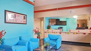 A lobby with blue sofas, a glass coffee table, and a reception desk. - Howard Johnson by Wyndham Houston Hobby Airport (Houston)