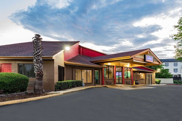 A hotel with a red roof, a covered entrance, and a well-lit facade. - Howard Johnson by Wyndham Houston Hobby Airport (Houston)