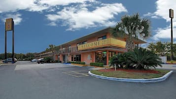 Welcome to our hotel, offering a convenient entrance via covered walkway and parking area, surrounded by lush greenery.