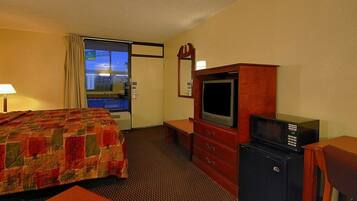 A hotel room with a bed, a TV, a microwave, and a dresser.