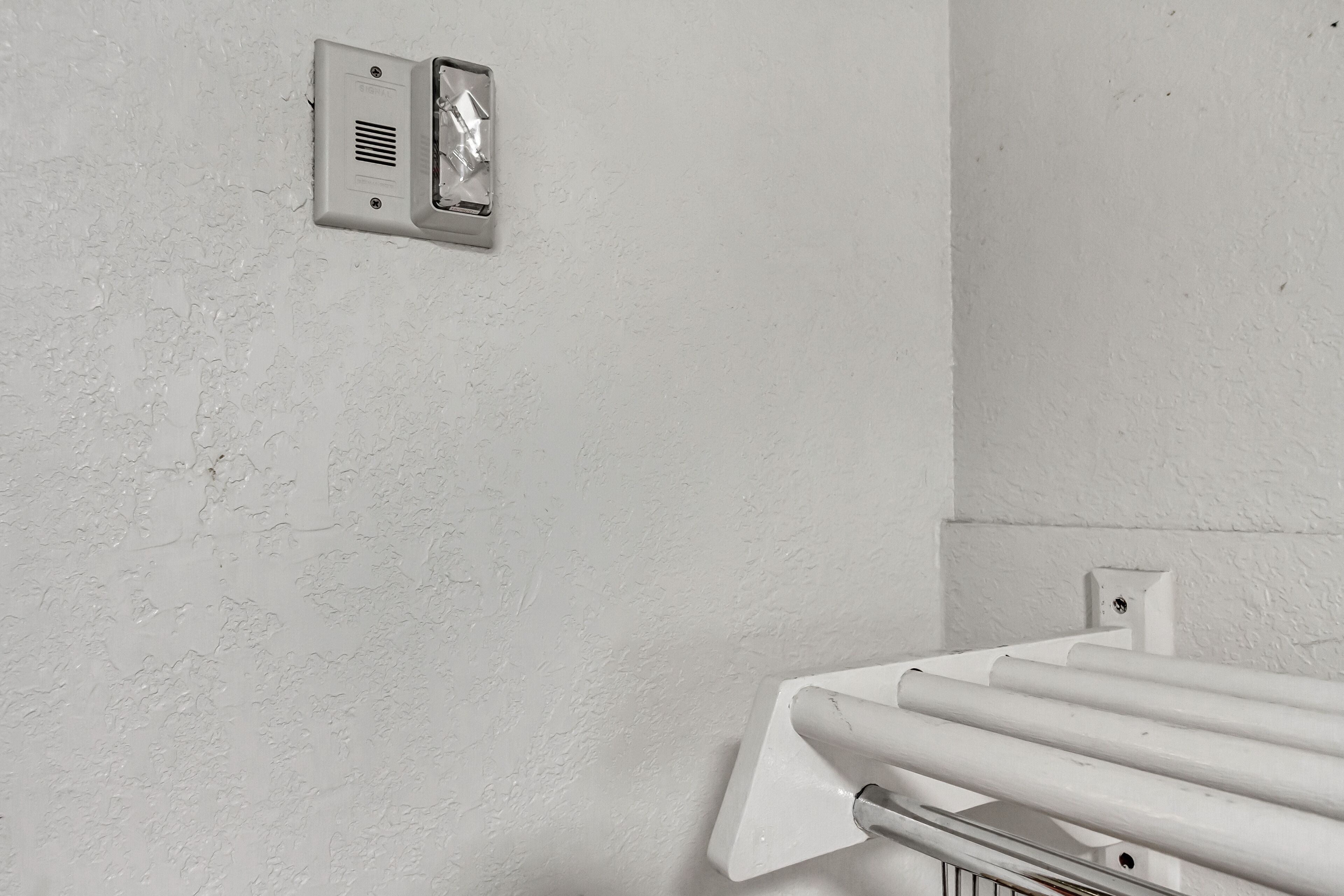 A white wall with a smoke detector and a white radiator.