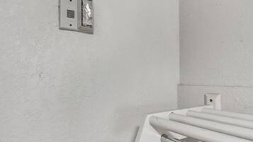 A white wall with a smoke detector and a white radiator.