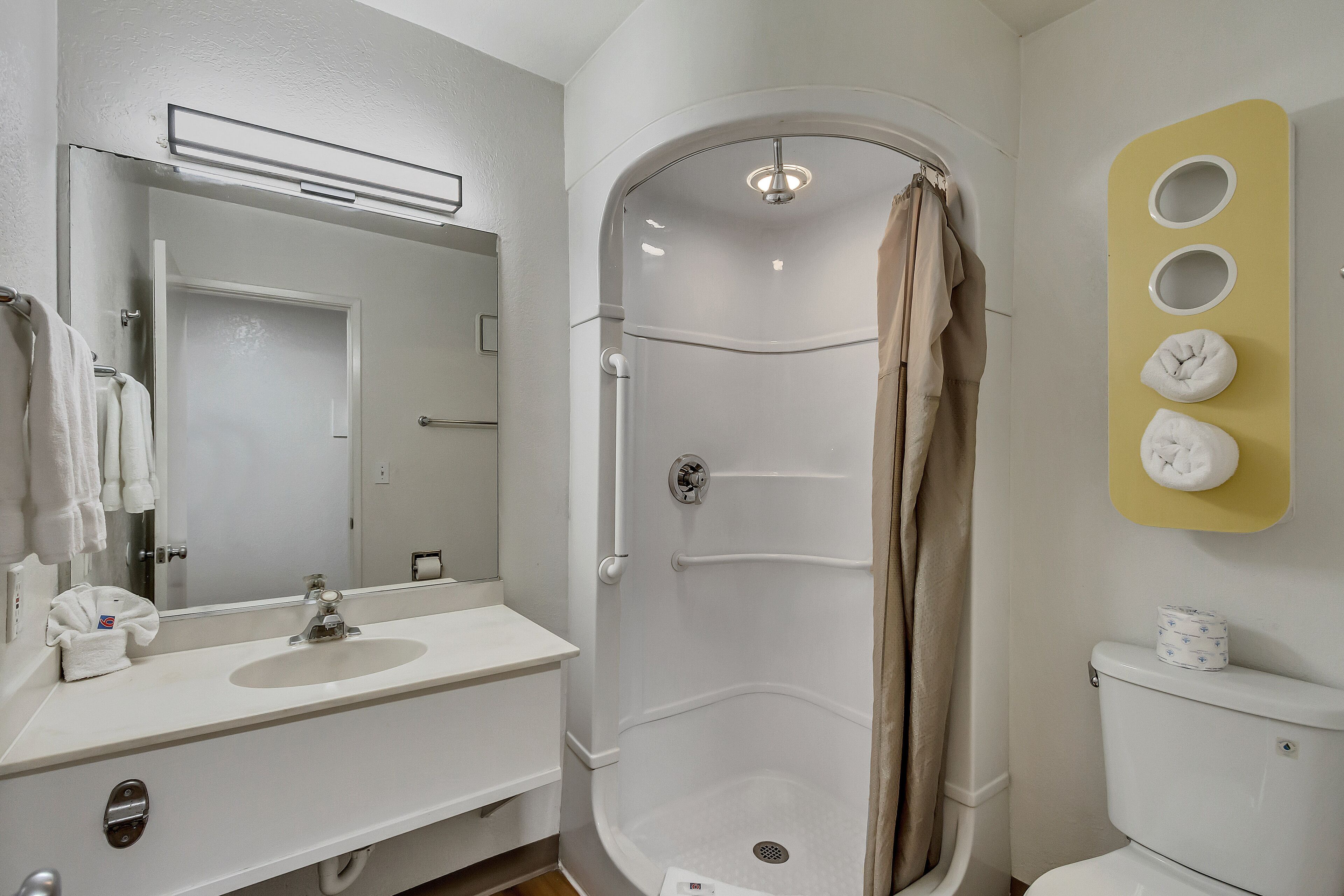 Un baño con lavamanos blanco, espejo y cabina de ducha.