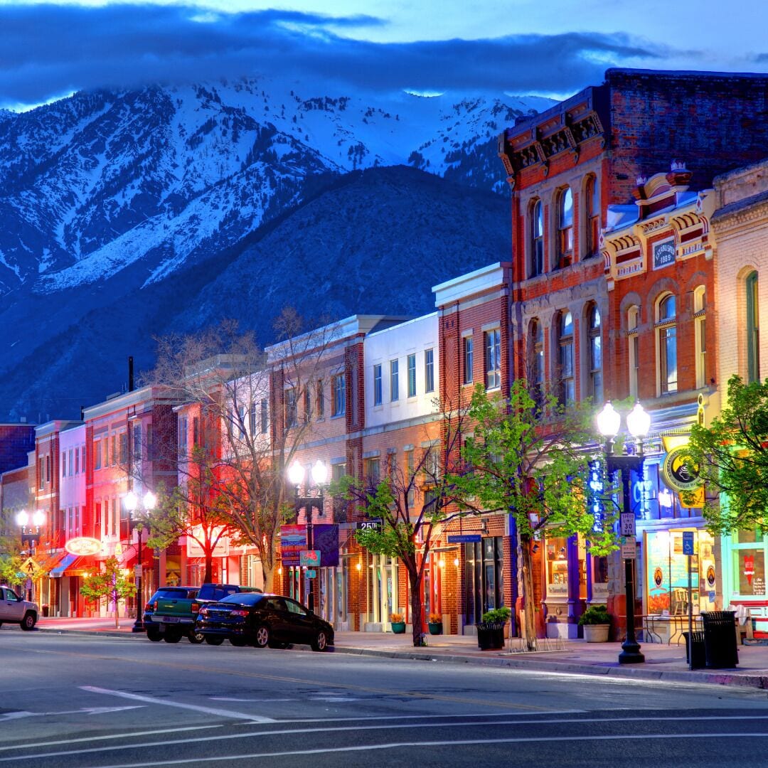 A street lined with historic buildings, a crosswalk, and a mountain backdrop.