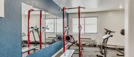 A gym with a bench, a pull-up bar, and exercise equipment.