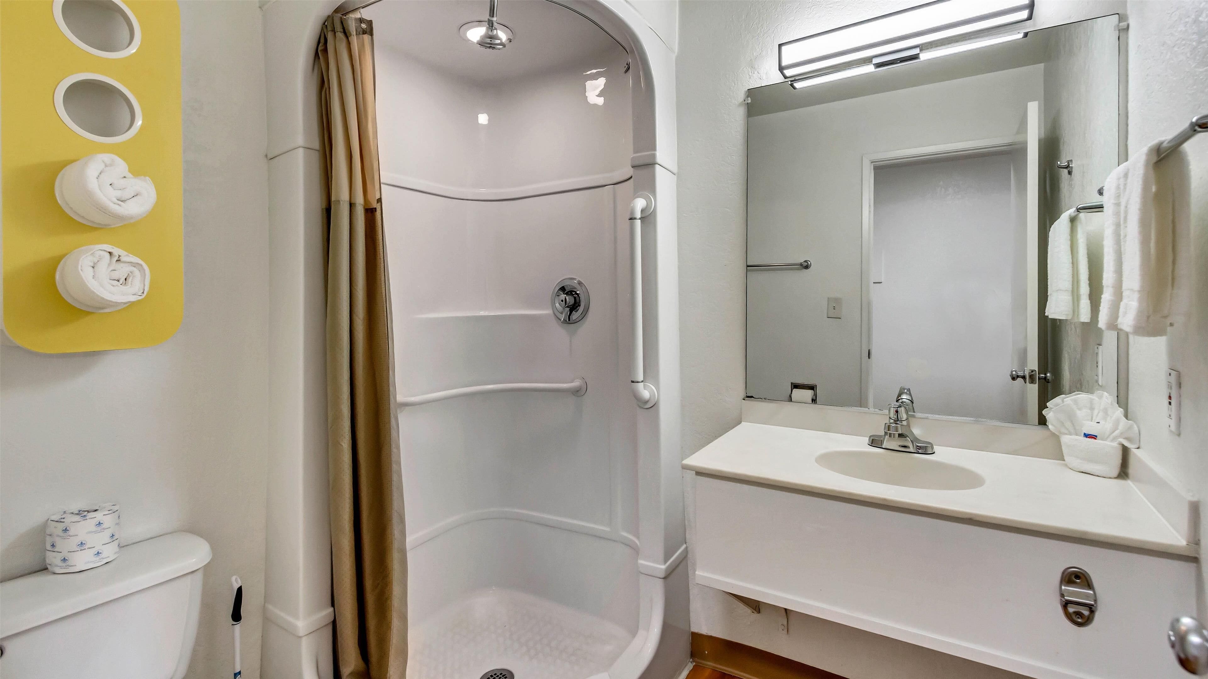 Une salle de bain équipée d’une douche, de toilettes, d’un lavabo et d’un miroir.