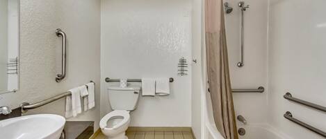 A bathroom with a toilet, sink, and shower. It includes grab bars and a towel rack.