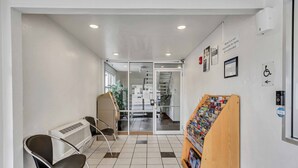 Zona de recepción de un hotel con área de espera, mostrador de recepción y un perchero para revistas.