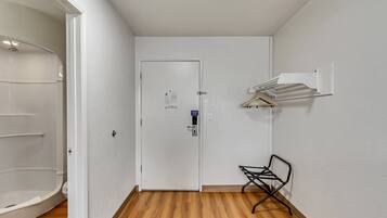 A hallway with a white door, a coat rack, and a small chair.