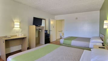 Une chambre d’hôtel avec deux lits, un bureau avec un téléphone, une télévision et un four à micro-ondes.