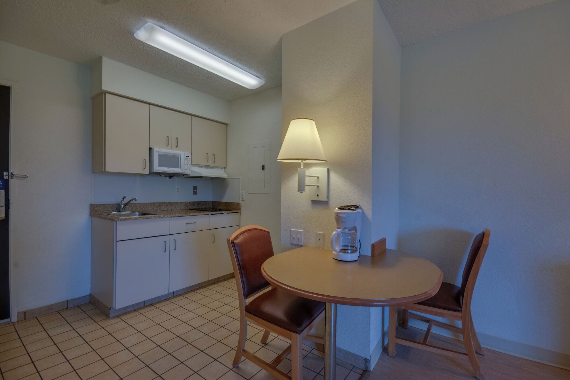 A compact kitchen with a microwave, a coffee maker, and a table with two chairs.