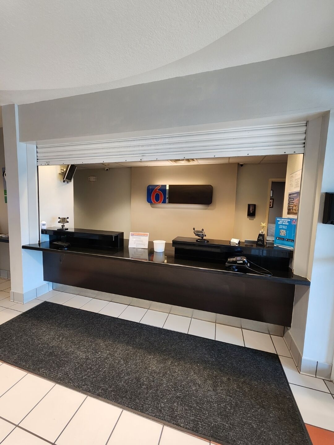A reception desk with a digital screen, a sign with the number 6, and a small trophy on the counter.