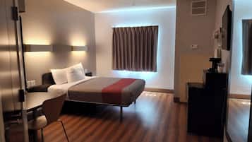 A modern hotel room with a bed, a desk, and a chair.