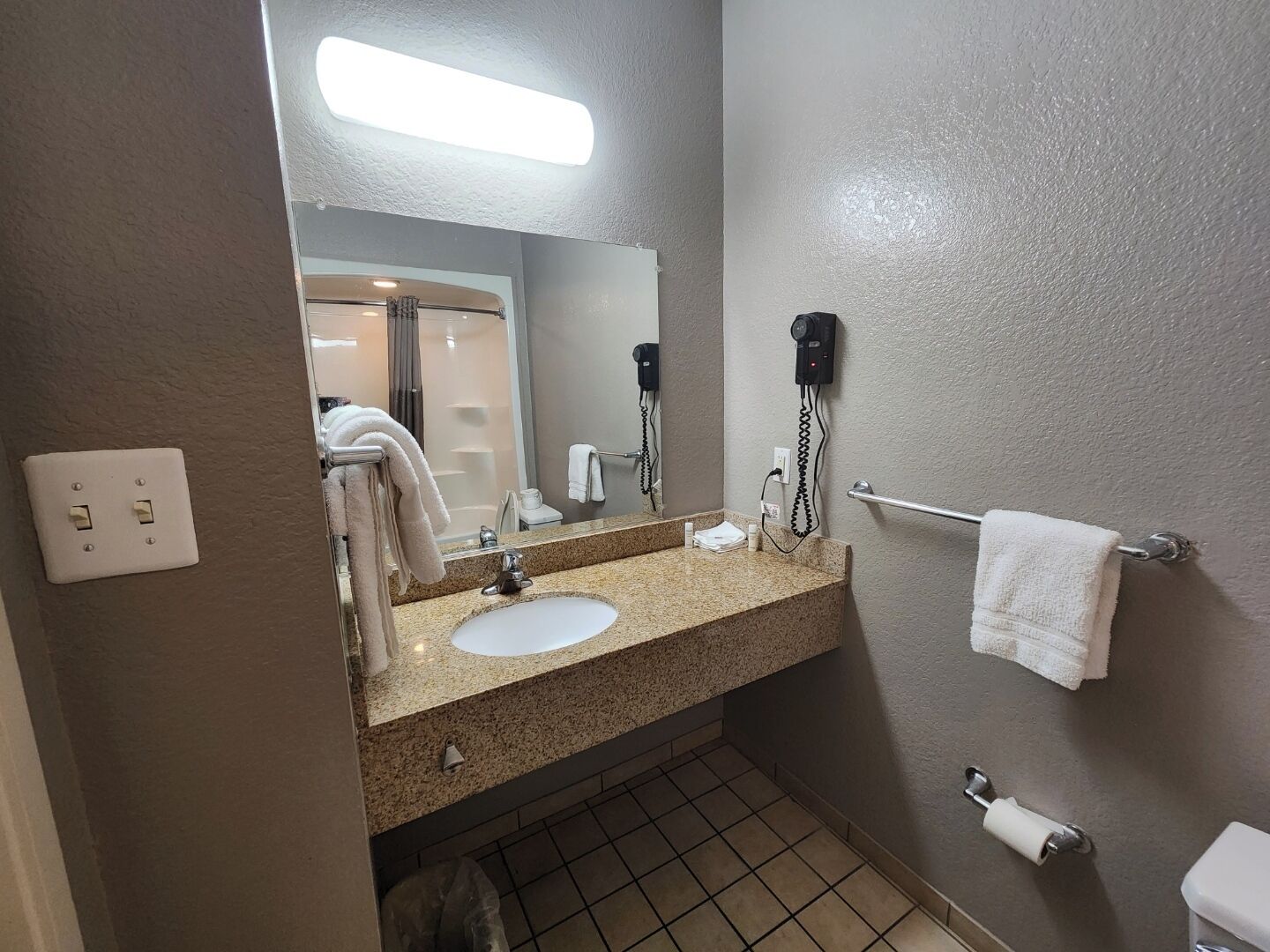 A bathroom with a sink, mirror, towel rack, and hairdryer.