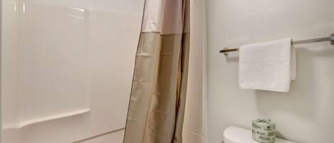 A bathroom with a bathtub, toilet, and a towel rack.