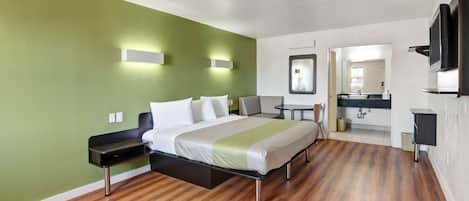 Une chambre d’hôtel moderne équipée d’un lit, de tables de chevet, d’un bureau, d’une chaise, d’un miroir et d’un téléviseur.