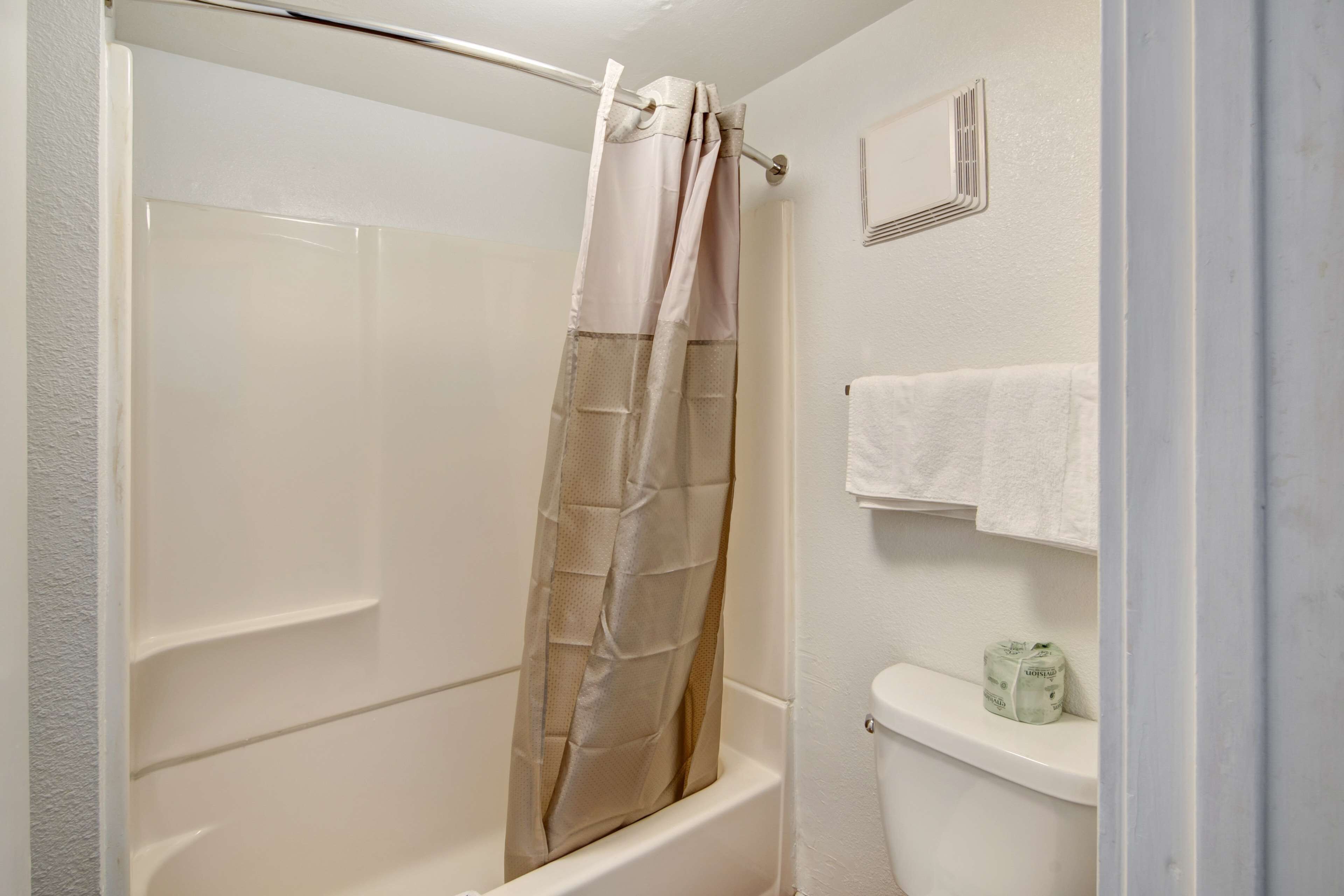 A bathroom with a shower curtain, a toilet, and a towel rack.