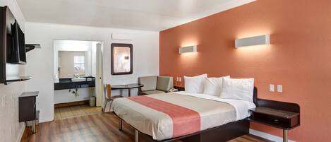 A modern hotel room with a bed, bedside table, and a view of the bathroom.