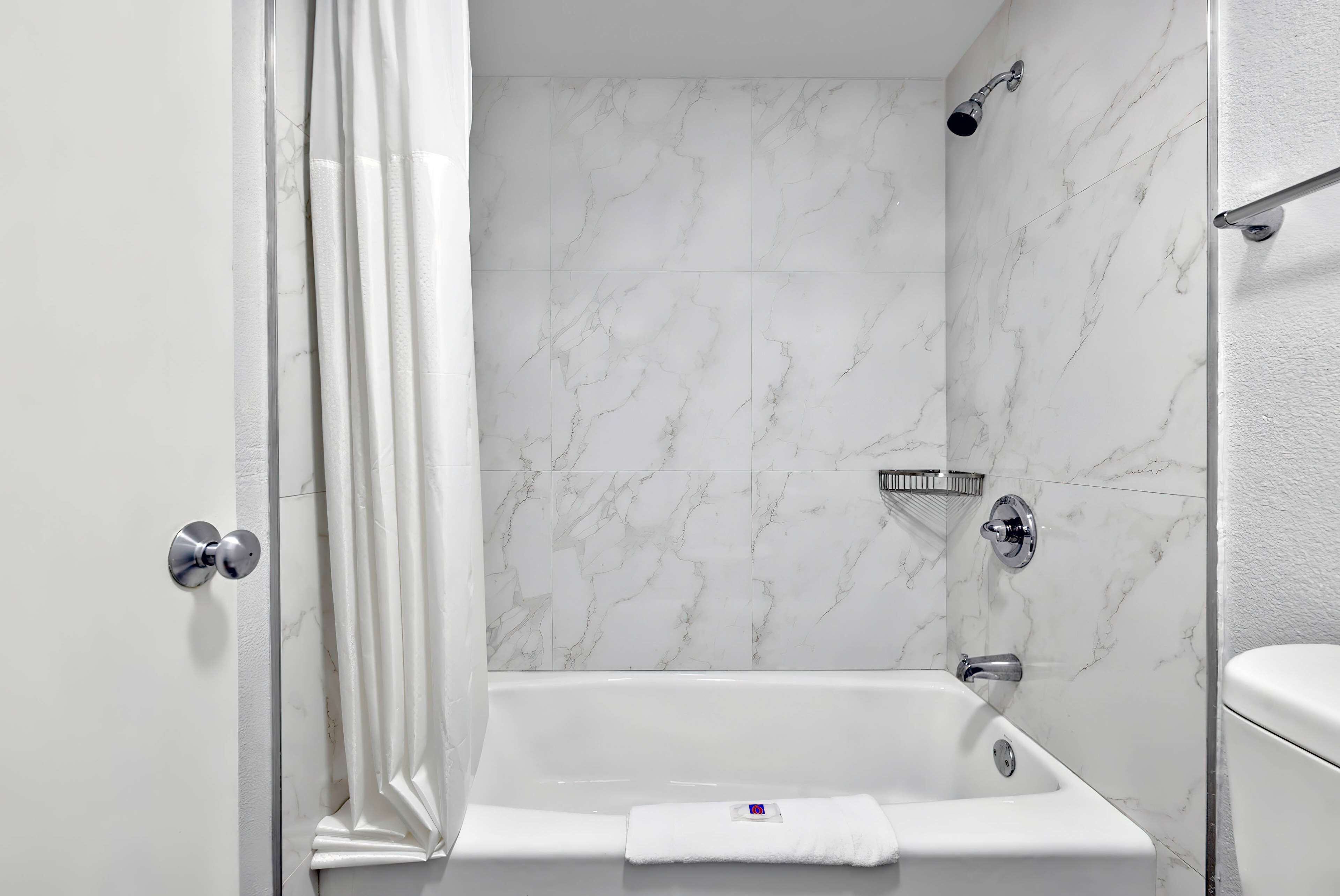 Un baño con una bañera blanca, ducha e inodoro.