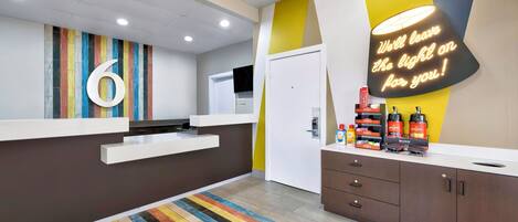 Un moderno vestíbulo de hotel con una recepción, un piso a rayas de colores y un letrero de neón en la pared.