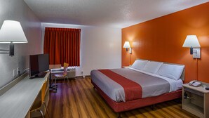 Une chambre d’hôtel équipée d’un lit, d’un bureau, d’une chaise et de deux lampes fixées au mur.